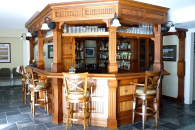 Ejemplo de bar en casa con barra de bar de galera rústico grande con armarios con paneles empotrados, puertas de armario de madera oscura, encimera de madera y suelo de pizarra