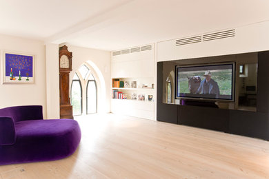 Foto de cine en casa nórdico con paredes blancas, suelo de madera clara y televisor colgado en la pared