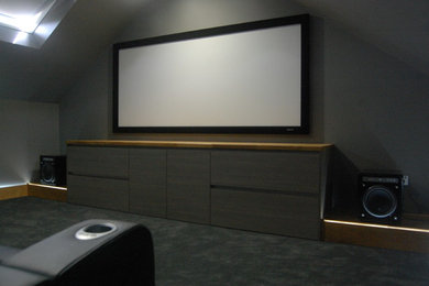 Diseño de cine en casa cerrado contemporáneo grande con paredes grises, moqueta y pantalla de proyección