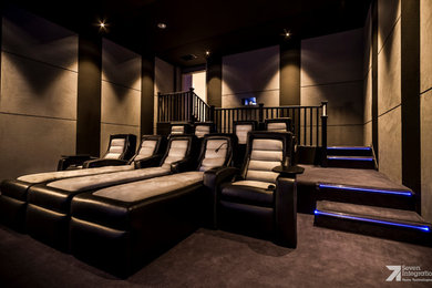Пример оригинального дизайна: изолированный домашний кинотеатр среднего размера в стиле модернизм с коричневыми стенами, ковровым покрытием и телевизором на стене