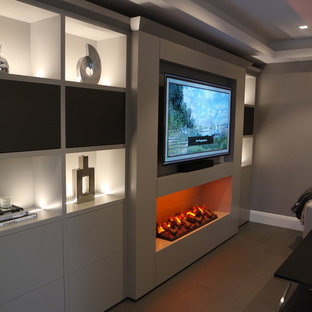 Immagine di un home theatre minimalista di medie dimensioni e aperto con pareti beige, pavimento in laminato, parete attrezzata e pavimento marrone