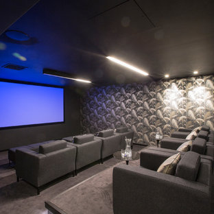 Medium sized contemporary enclosed home cinema in London with grey walls, a projector screen, grey floors and carpet.