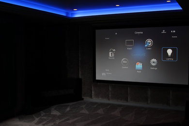 Large contemporary enclosed home cinema in Hertfordshire with grey walls, carpet, a projector screen and beige floors.