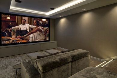 Imagen de cine en casa cerrado contemporáneo grande con paredes marrones, moqueta, pantalla de proyección y suelo beige