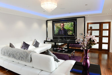 Ejemplo de cine en casa clásico renovado de tamaño medio con paredes grises, suelo de madera oscura y televisor colgado en la pared