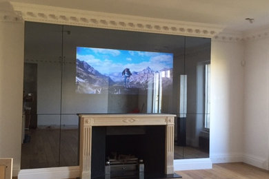 Klassisk inredning av ett mycket stort avskild hemmabio, med ljust trägolv och en väggmonterad TV