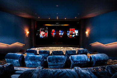 Photo of a large contemporary enclosed home cinema in London with blue walls, carpet, a projector screen and blue floors.