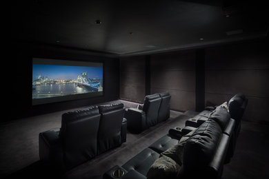 Immagine di un grande home theatre minimalista chiuso con pareti nere, moquette e TV a parete