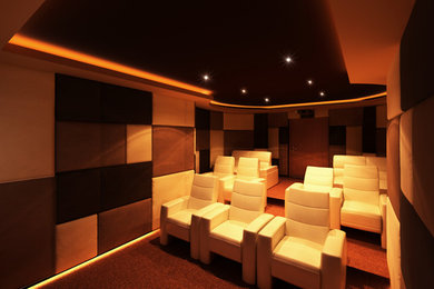 Medium sized modern enclosed home cinema in Other with multi-coloured walls, carpet and a projector screen.