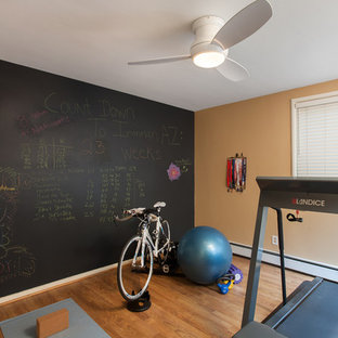 Idee per una sala pesi stile americano di medie dimensioni con pareti gialle e pavimento in legno massello medio