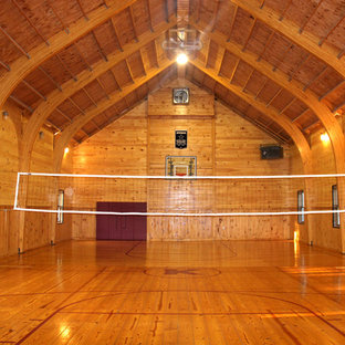 Immagine di un ampio campo sportivo coperto country con pareti marroni, pavimento in legno massello medio e pavimento marrone