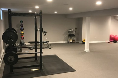 This is an example of a large traditional home weight room in New York with grey walls, carpet and grey floors.