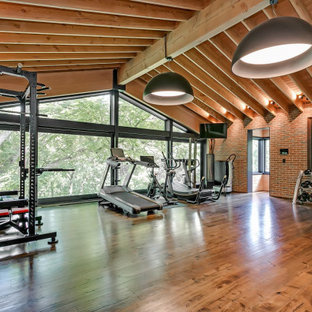 Ispirazione per un'ampia sala pesi american style con pareti rosse, parquet scuro e pavimento marrone