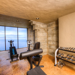 Immagine di una grande sala pesi mediterranea con pareti beige, pavimento in cemento e pavimento arancione
