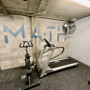 Immagine di una grande palestra multiuso industriale con pareti grigie, pavimento in cemento, pavimento grigio e travi a vista