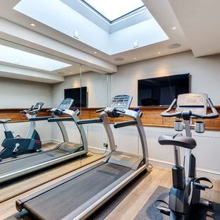 Example of a small trendy light wood floor multiuse home gym design in London with white walls