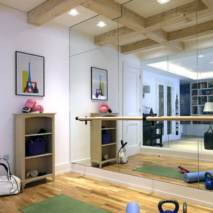 Foto di una palestra in casa design con pareti bianche, pavimento in legno massello medio e pavimento marrone