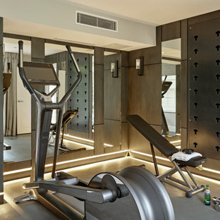 This is an example of a contemporary multi-use home gym in London with grey walls and grey floors.