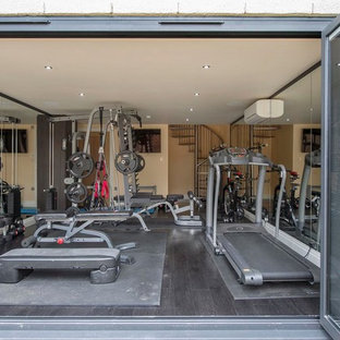 Ispirazione per una palestra multiuso contemporanea di medie dimensioni con pareti beige, pavimento nero e parquet scuro