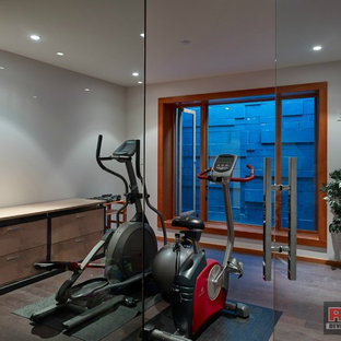 Esempio di una palestra multiuso moderna di medie dimensioni con pareti grigie, parquet scuro e pavimento marrone