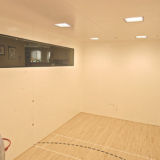 Immagine di un ampio campo sportivo coperto stile rurale con pareti bianche e parquet chiaro