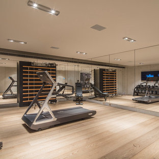 Immagine di una grande palestra multiuso minimal con parquet chiaro e pareti grigie
