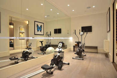 Photo of a modern multi-use home gym in London with grey walls and beige floors.