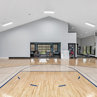 Foto di un ampio campo sportivo coperto country con pareti grigie, parquet chiaro e pavimento marrone