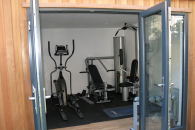 Cette image montre une salle de sport design multi-usage et de taille moyenne avec un mur blanc et parquet clair.