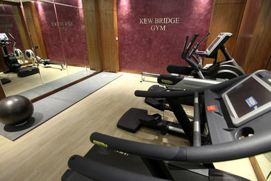 Photo of a medium sized modern multi-use home gym in London with purple walls and light hardwood flooring.
