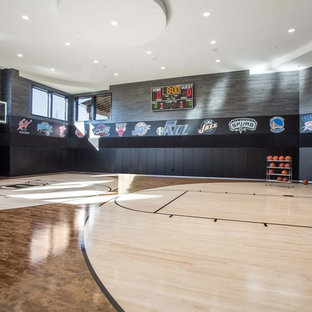 Ispirazione per un ampio campo sportivo coperto minimal con pareti nere, parquet chiaro e pavimento beige