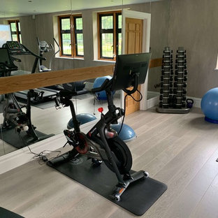 Ispirazione per una sala pesi design di medie dimensioni con pareti grigie, pavimento in legno verniciato e pavimento beige