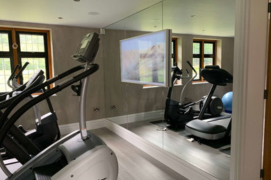 Foto de sala de pesas contemporánea de tamaño medio con paredes grises, suelo de madera pintada y suelo beige