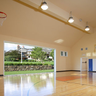 Immagine di un grande campo sportivo coperto tradizionale con pareti gialle, parquet chiaro e pavimento beige