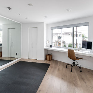 Ispirazione per una palestra multiuso design di medie dimensioni con pareti bianche, parquet chiaro e pavimento marrone