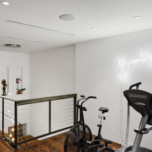 Contemporary home gym in New York with white walls and dark hardwood floors.