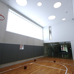 Ispirazione per un campo sportivo coperto design di medie dimensioni con pareti grigie e pavimento in legno massello medio