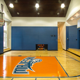Aménagement d'un grand terrain de sport intérieur classique avec un mur bleu et un sol en bois clair.
