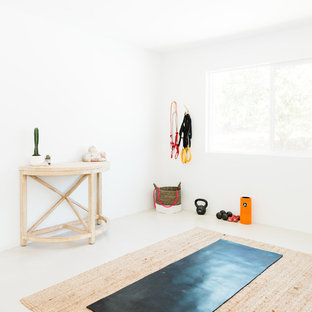 Immagine di uno studio yoga stile americano di medie dimensioni con pareti bianche, pavimento in cemento e pavimento bianco