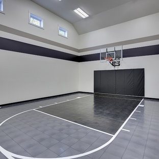 Immagine di un ampio campo sportivo coperto classico con pareti grigie, pavimento in vinile e pavimento grigio