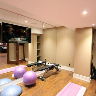 Foto di uno studio yoga tradizionale di medie dimensioni con pareti beige, pavimento in laminato e pavimento marrone