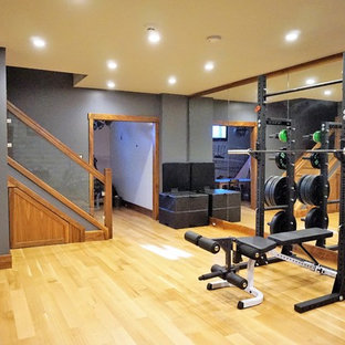 Esempio di una sala pesi stile rurale di medie dimensioni con pareti grigie, parquet chiaro e pavimento beige