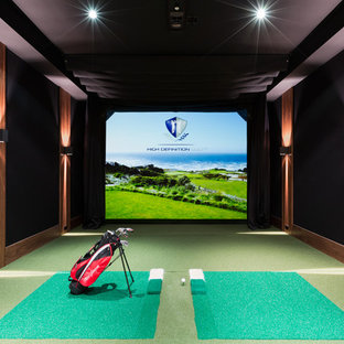 Aménagement d'un grand terrain de sport intérieur classique avec un mur noir, moquette et un sol vert.