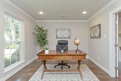Elegant freestanding desk medium tone wood floor study room photo in Houston with gray walls