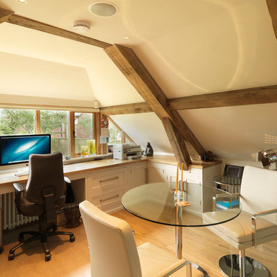 Study room - large country built-in desk medium tone wood floor study room idea in Hampshire with beige walls