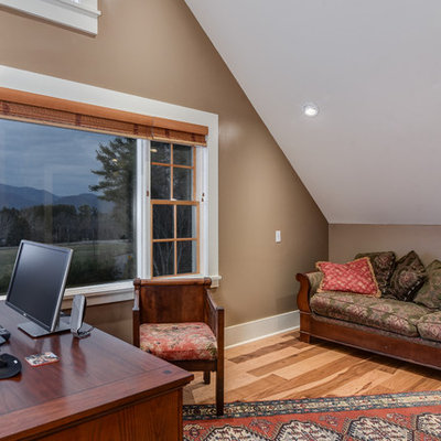 Home office - large farmhouse freestanding desk light wood floor home office idea in Other with brown walls and a two-sided fireplace