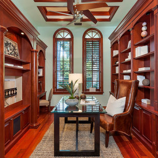 Mittelgroßes Mediterranes Arbeitszimmer ohne Kamin mit Arbeitsplatz, grüner Wandfarbe, braunem Holzboden, freistehendem Schreibtisch und rotem Boden in Miami