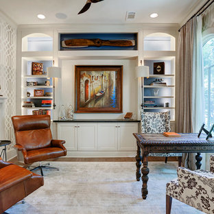Immagine di uno studio chic di medie dimensioni con libreria, pareti beige, parquet chiaro, camino classico, cornice del camino in pietra, scrivania autoportante e pavimento marrone