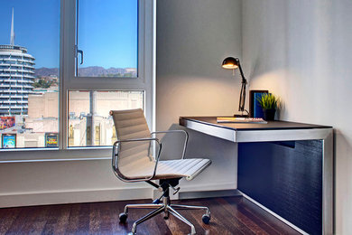 На фото: большой кабинет в стиле модернизм с бежевыми стенами, темным паркетным полом и встроенным рабочим столом без камина