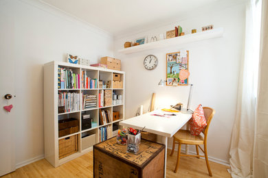 Modelo de sala de manualidades ecléctica pequeña con paredes blancas, suelo de madera clara y escritorio independiente